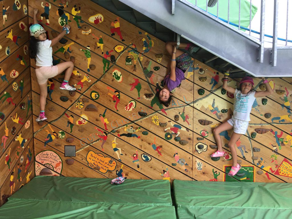 Children climbing a colorfully painted wooden bouldering wall